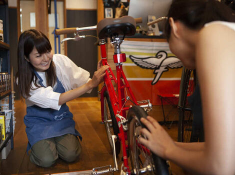 自転車の状態を確認する女性スタッフ